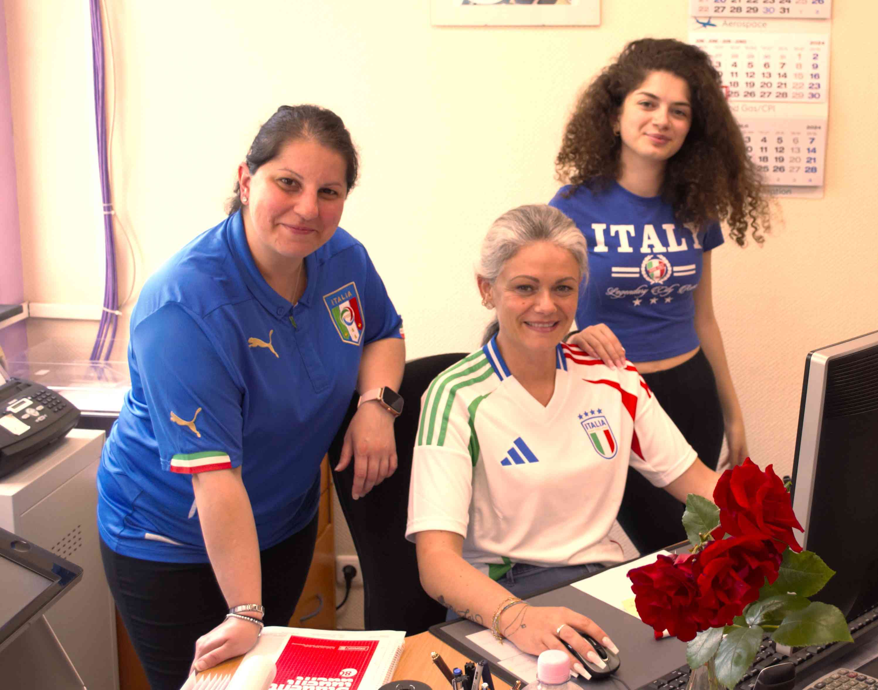 It shows three female employees working in an office. They wear jerseys or T-shirts that point to Italy.
