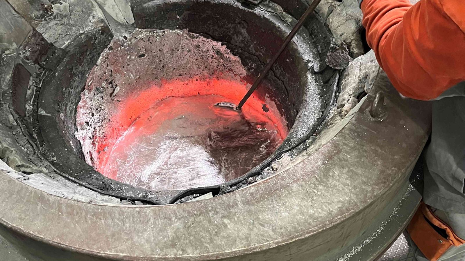 Zu sehen ist ein Ofen in dem metallisches Material verrührt wird.